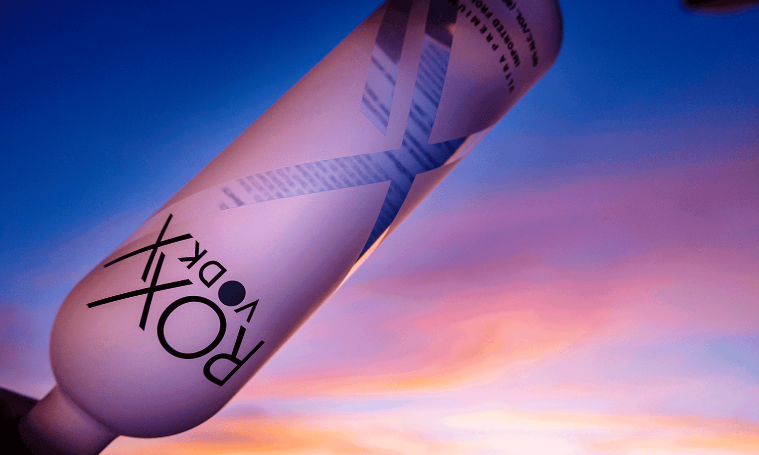 Image of ROXX Vodka with a sunset sky behind the bottle.
